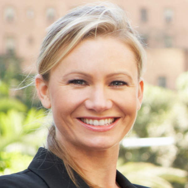 Smiling woman outdoors with blurred background.