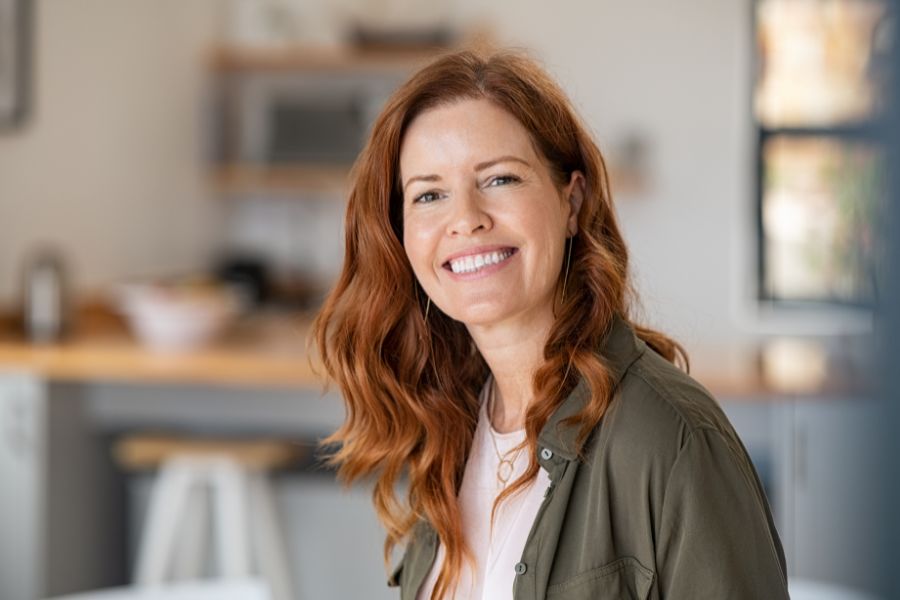 Smiling woman with red hair in a casual setting.