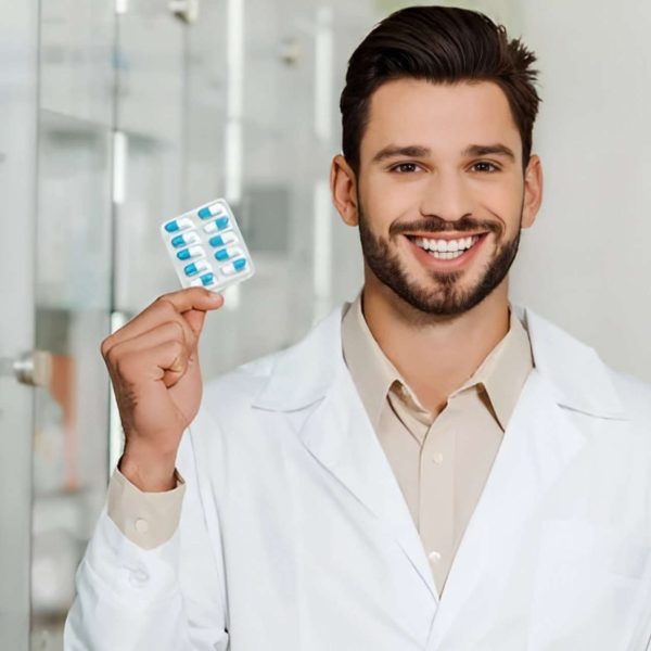 Smiling pharmacist holding a blister pack of blue pills.