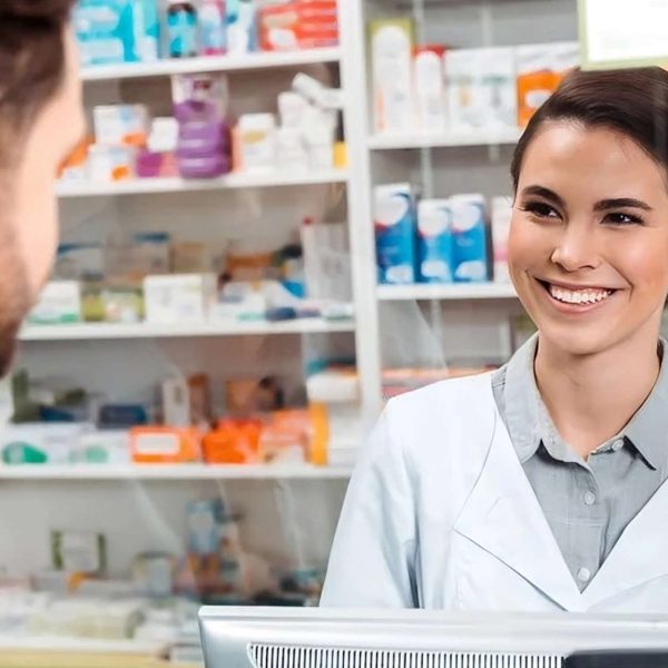Pharmacist smiling and assisting a customer at the pharmacy counter.